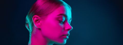 Jeune femme au visage éclairé d'une lumière rose fluo