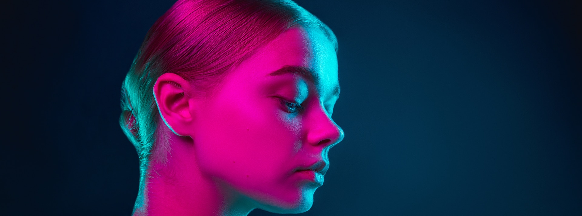 Jeune femme au visage éclairé d'une lumière rose fluo