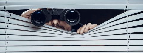 96 % des entreprises surveillent leurs employés au travail Personne derrière une persienne avec des jumelles