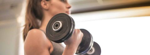 Le nouveau fitness Jeune femme de profil avec poids dans les mains