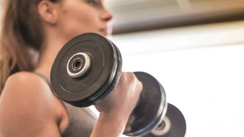 Le nouveau fitness Jeune femme de profil avec poids dans les mains