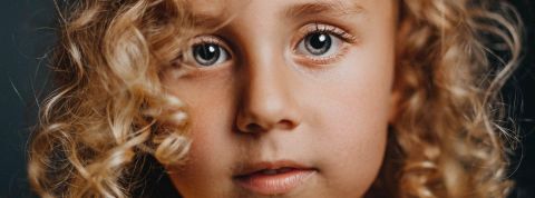 Scanner le visage des enfants en ligne ? Visage d'une petite fille aux cheveux bouclés en gros plan