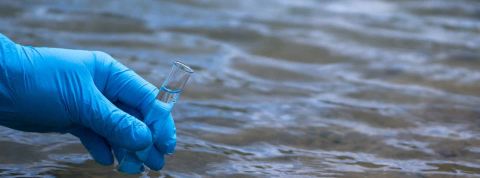 Un nouveau traitement pourrait permettre d'éliminer les produits chimiques des sources d'eau La main d’un homme dans un gant bleu prend un gros plan d’eau dans un tube à essai pour mesurer la pollution de l’eau
