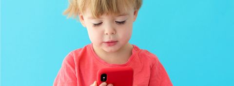Un enfant de 3 ans en tshirt rouge les yeux rivés sur un smartphone rouge