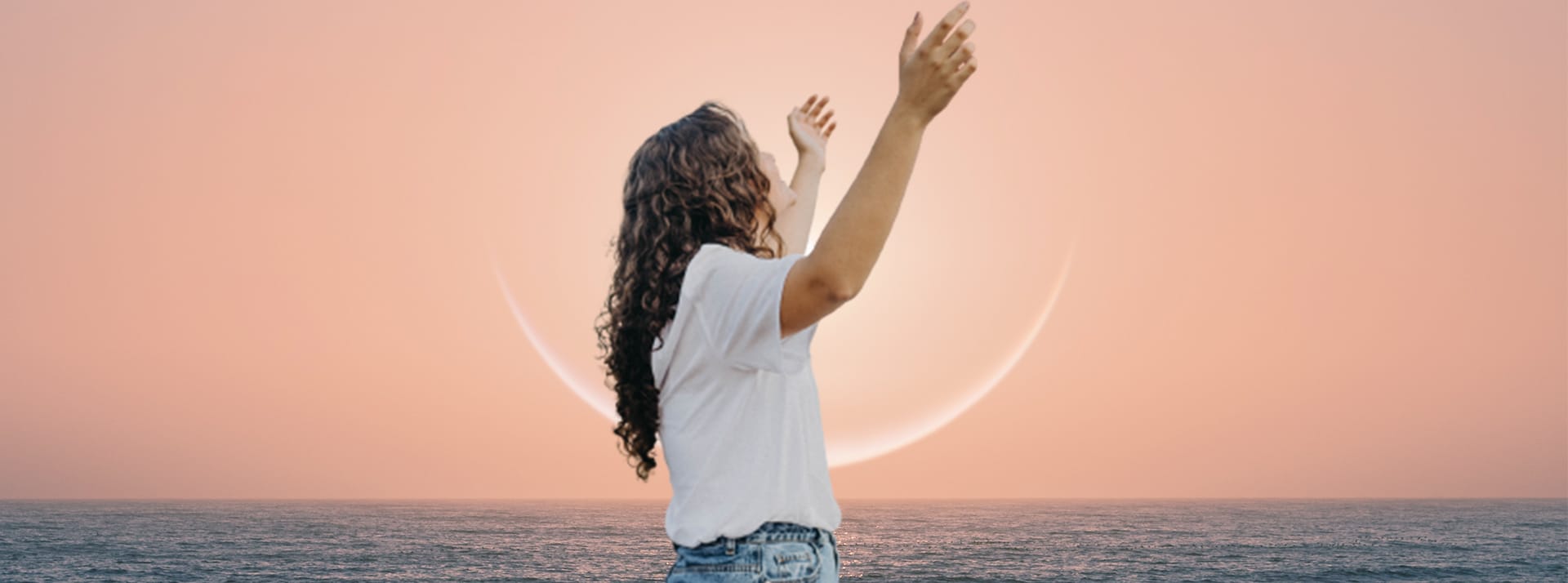 Une femme les bras au ciel au soleil couchant
