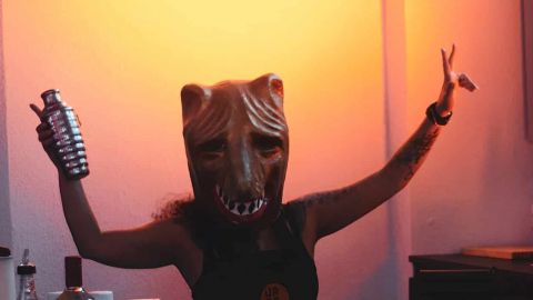 Femme avec un masque de loup^et un shaker à cocktail dans une main