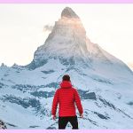 Un homme de dos face à une montagne recouverte de neige