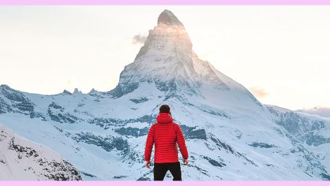 Un homme de dos face à une montagne recouverte de neige