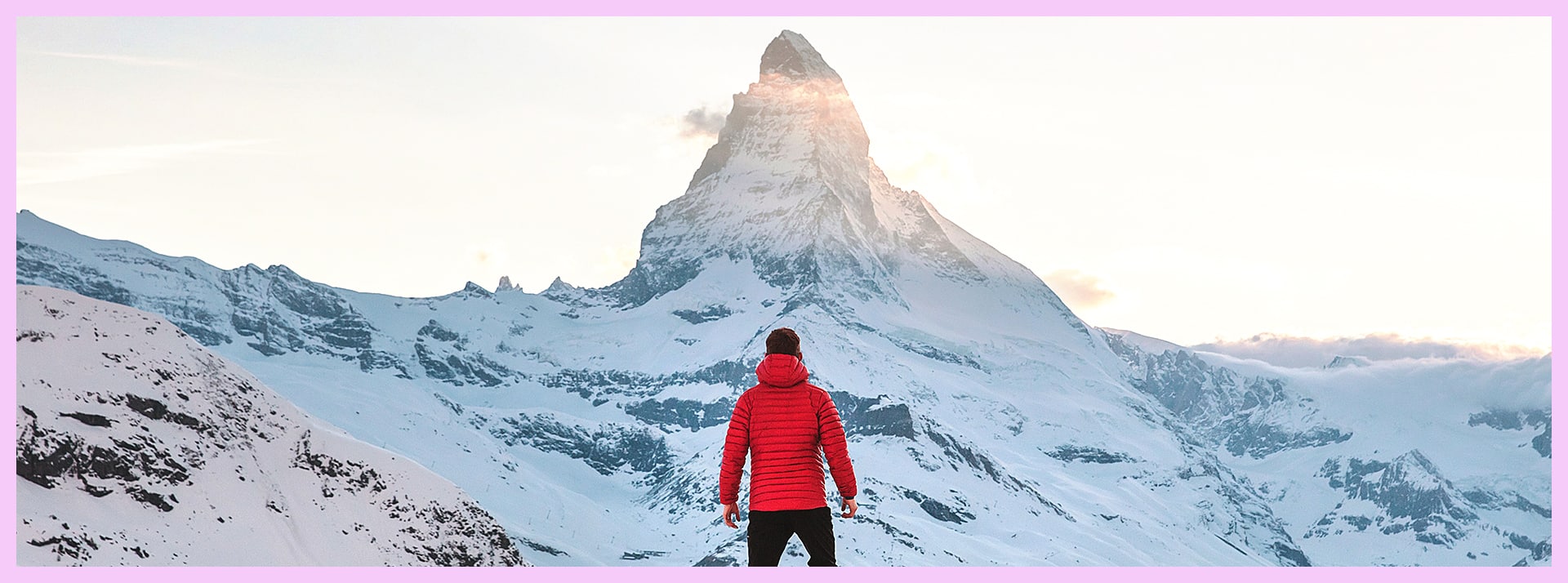 Un homme de dos face à une montagne recouverte de neige