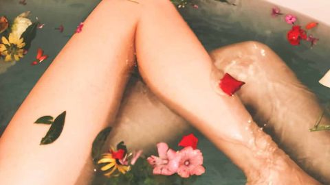 Jambe d'une femme dans une baignore avec des pétales de fleurs