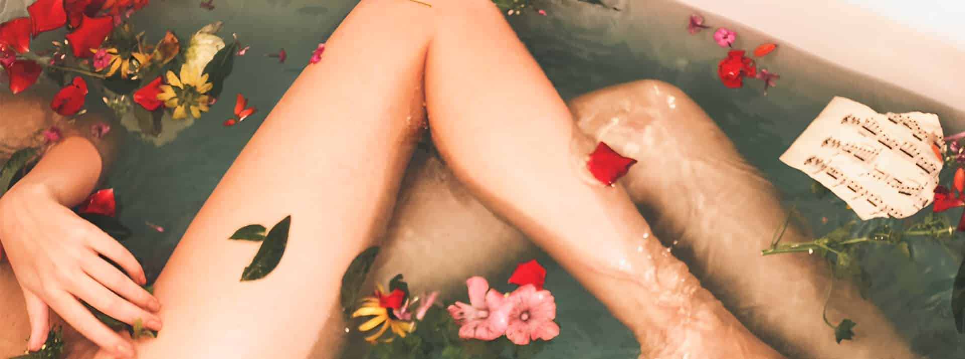 Cosmétiques bio et naturel s'imposent comme des incontournables dans les salles de bains. - L'ADN Jambe d'une femme dans une baignore avec des pétales de fleurs