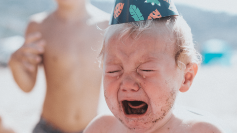 Un bébé pleur porte un chapeau d'anniversaire