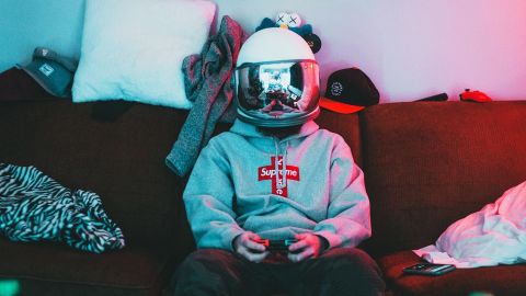 Un gamer portant un casque de moto miroir, assis dans son canapésans