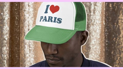 Homme noir portant une casquette I love Paris sur un rideau pailleté