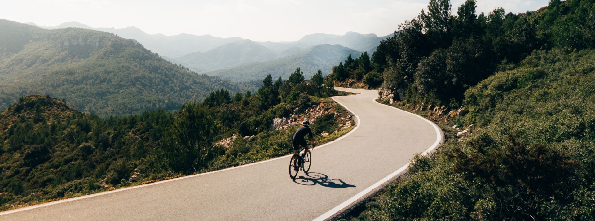 Une homme à vélo sur une route dans les montagnes