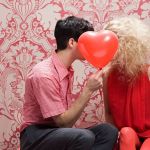 Couple s'embrassant derrière un ballon en forme de coeur