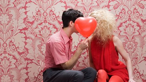 Couple s'embrassant derrière un ballon en forme de coeur