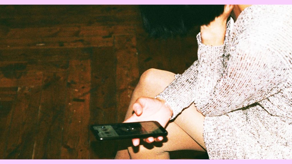 Une fille assisse en robe avec un téléphone en main