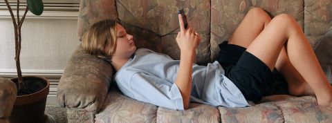 Enfant et écrans : c'est encore aux femmes de gérer une ado allongée sur un canapé regarde son téléphone