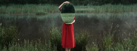 Selon la science, l'estime de soi est le premier pas vers le bonheur. Femme se cachant derrière un miroir