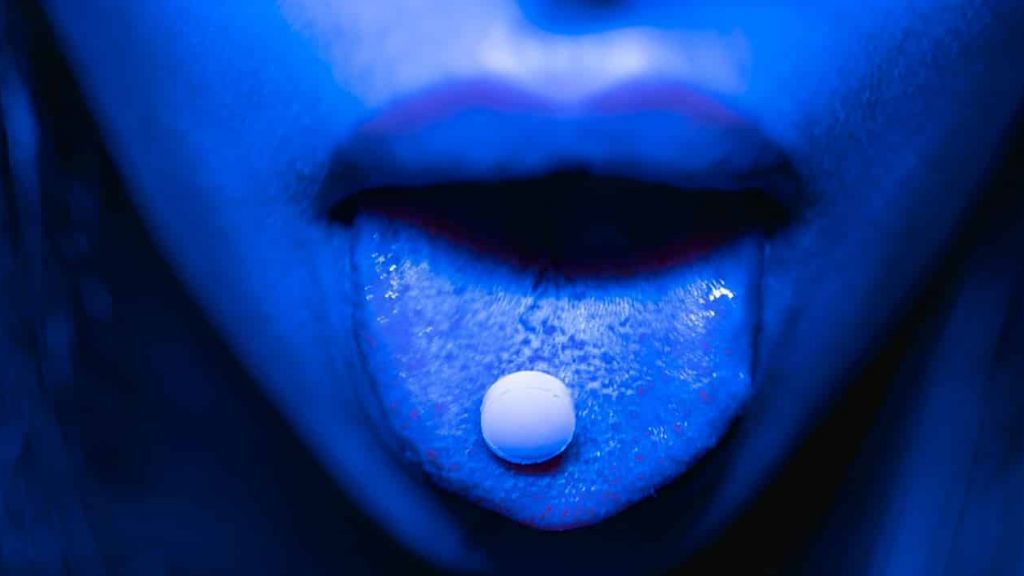 Femme tirant la langue avec une pillule