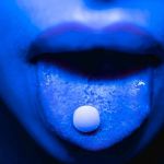 Femme tirant la langue avec une pillule