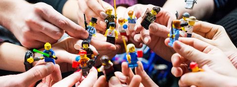 Leadership de demain : moins de vision, plus d'attention Des mains adultes tiennent des mini personnages LEGO, comme une équipe