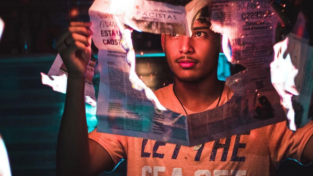 media brule Un jeune homme tient un journal qui brûle