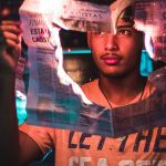 Un jeune homme tient un journal qui brûle