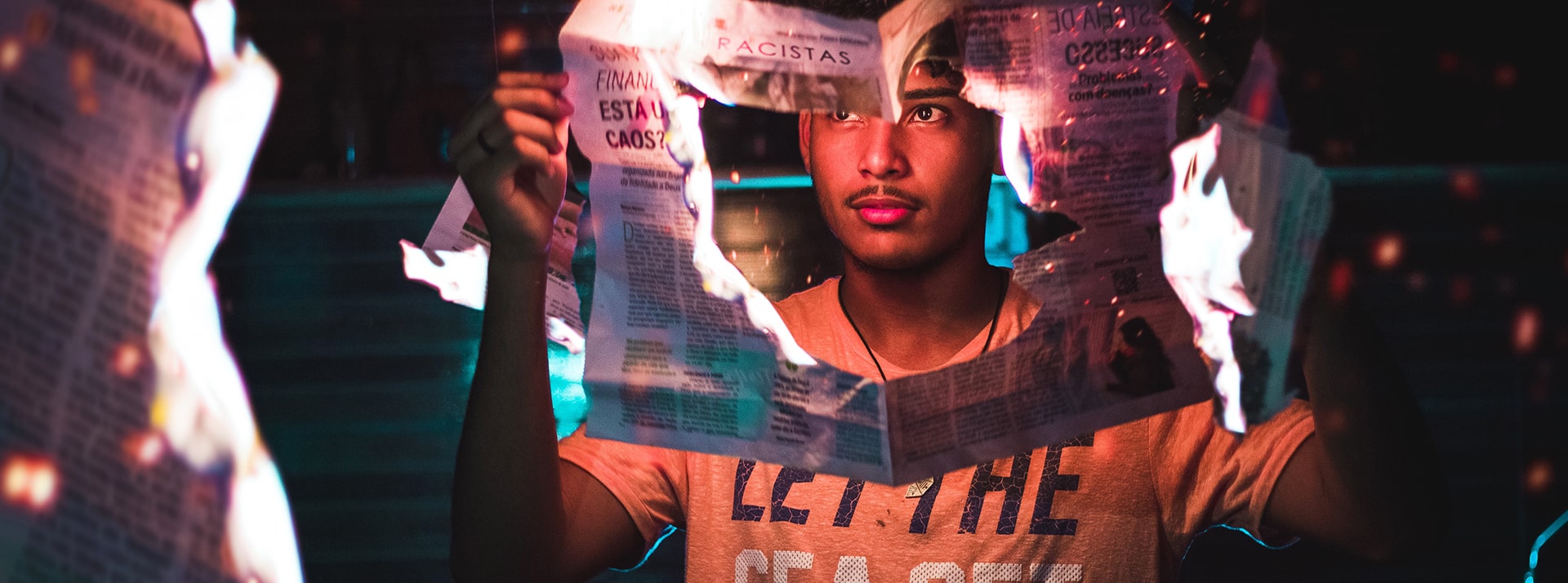 media brule - L'ADN Un jeune homme tient un journal qui brûle