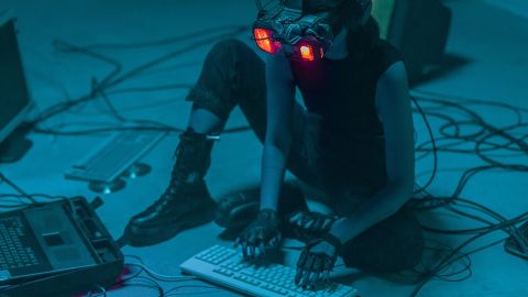 pollution numérique : une femme assise avec un casque VR et entourée de cables