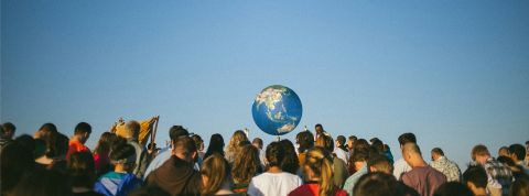 Crise climatique : la manipulation de masse peut-elle nous sauver ? une foule de dos et une planète au fond