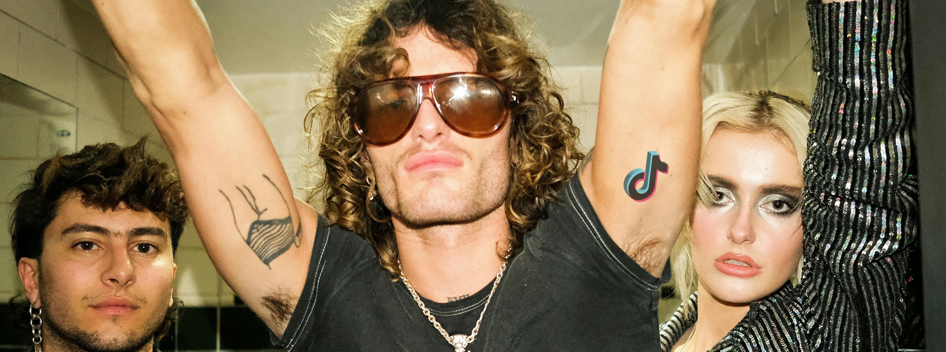 Comment TikTok entretien la panique des tiktokeurs pour défendre sa position aux USA - L'ADN Deux jeunes hommes et une femme blondeambiance rock avec tatouage TikTok