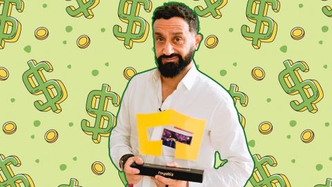 Hanouna souriant, portant un trophée Royaltiz sur fond de dollars