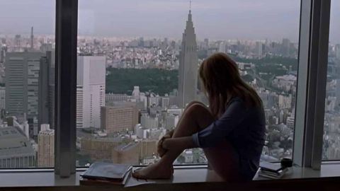 Une silhouette de femme qui regarde la ville d'une fenêtre