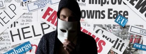 Une étude dépeint une France particulièrement vulnérable aux fake news Homme avec un masque anonymous devant des coupures de journaux