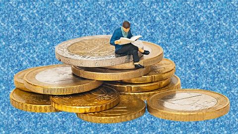 Un petit personnage miniature en plastique assis sur des pièces