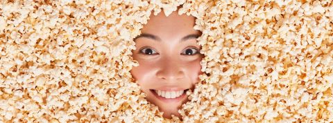 Comment Big Food exploite la tendance Anti-Diet pour protéger ses intérêts Le visage d'une jeune Asiatique ensevelie sous des pop corn