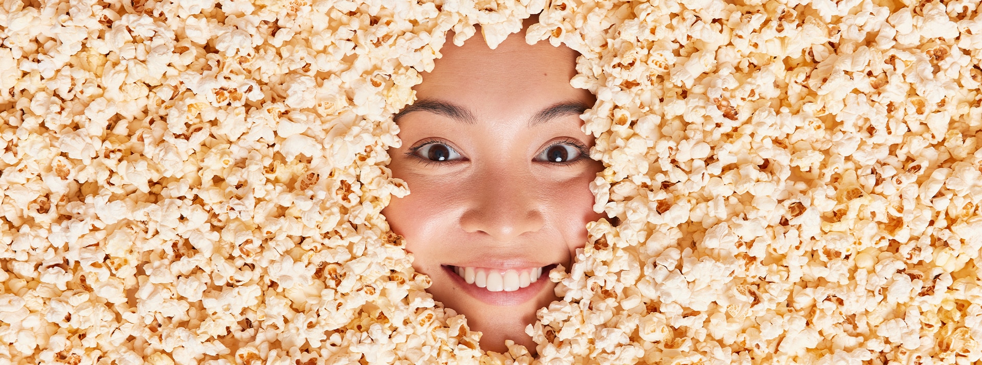 Comment Big Food exploite la tendance Anti-Diet pour protéger ses intérêts - L'ADN Le visage d'une jeune Asiatique ensevelie sous des pop corn