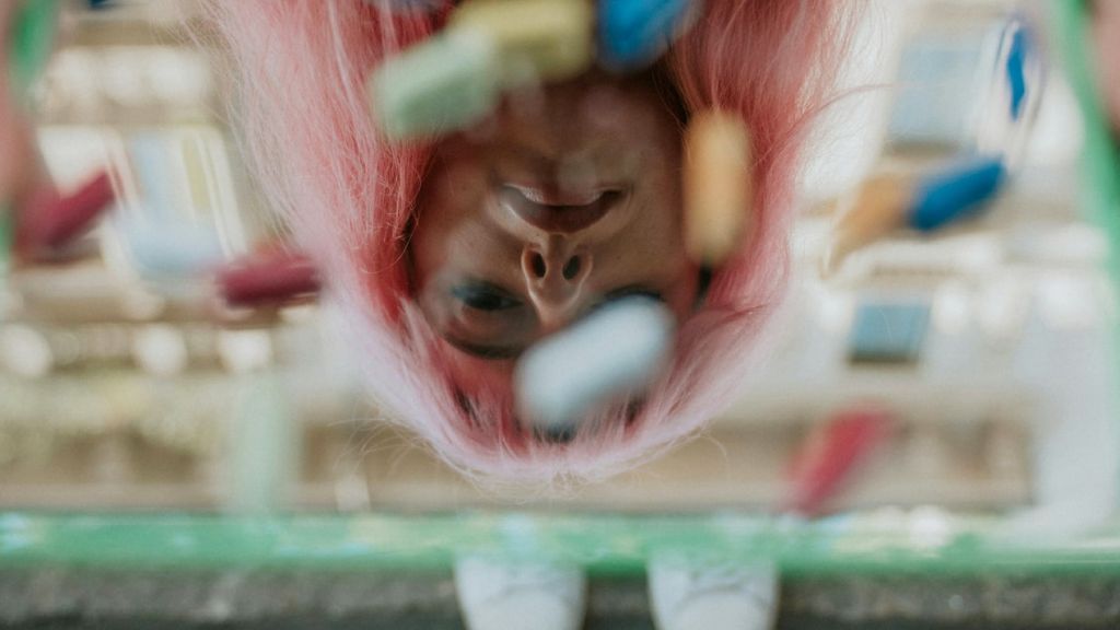 Une jeune fill tient un miroir recouvert de pilules