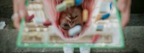 Biohacking et quantify self, la mesure du soi pour ne pas mourir Une jeune fill tient un miroir recouvert de pilules