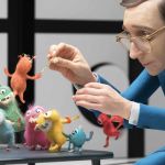 Un homme en costume bleu foncé domptes des petits monstres colorés