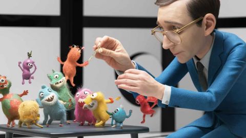 Un homme en costume bleu foncé domptes des petits monstres colorés