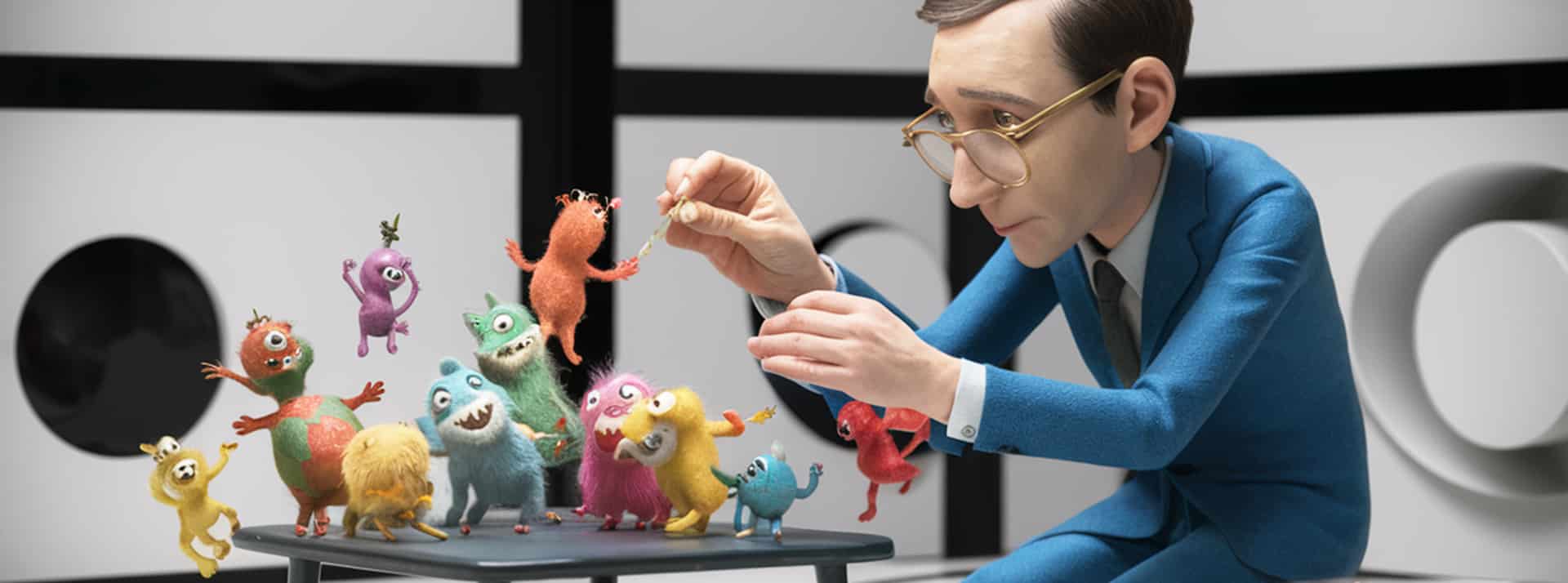 Un homme en costume bleu foncé domptes des petits monstres colorés