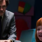 Un petite fille pleure avec un homme au second plan, dans la pénombre