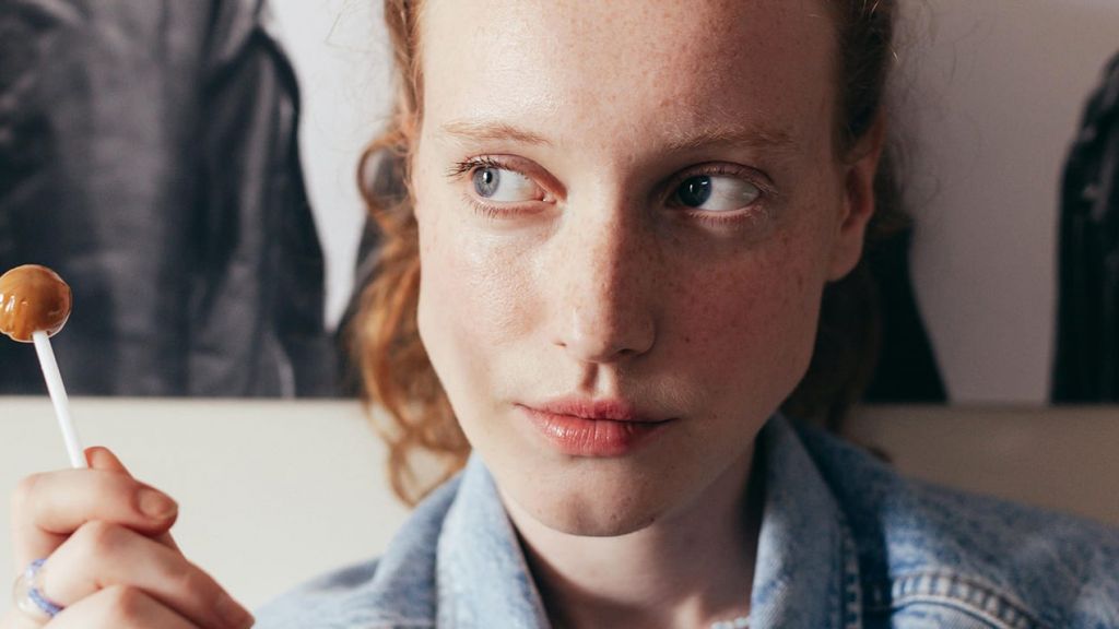Une jeune femme rousse, regard au ciel avec une sucette