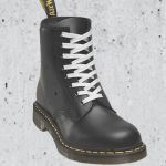 Une doc Martens noire avec lacet blanc sur béton brut