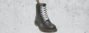 Une doc Martens noire avec lacet blanc sur béton brut