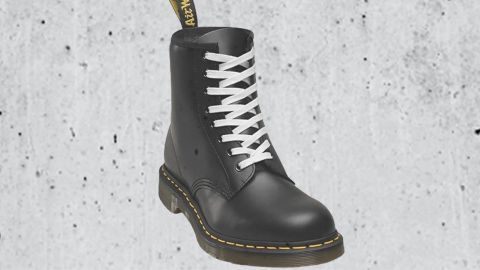 Une doc Martens noire avec lacet blanc sur béton brut