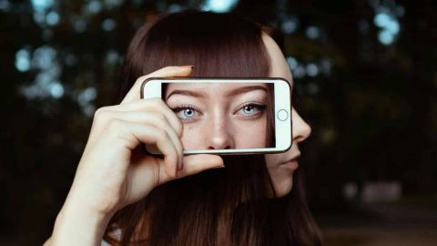 une fille qui pose avec un smartphone sur le côté de sa tête
